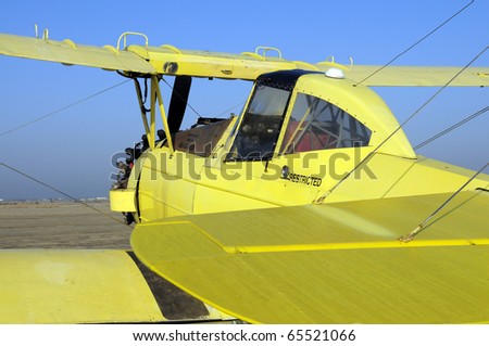 Yellow crop duster biplane with spray nozzles mounted on wing trailing edge