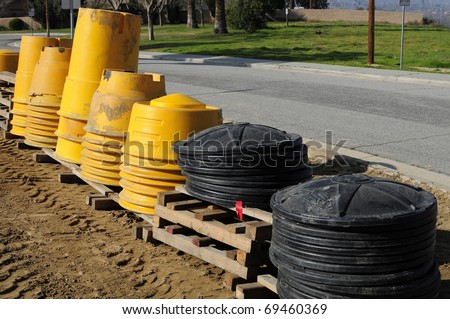 Stacks of plastic barrels to be filled with sand and used as temporary barriers on road construction project