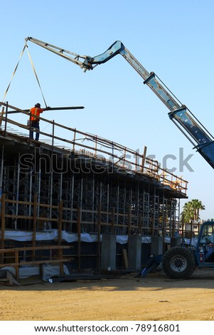 Construction job site: Lifting lumber to building roof with crane