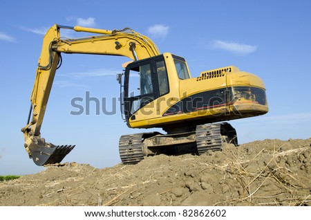 Construction job site: A hydraulic excavator sits atop a hill of its own making