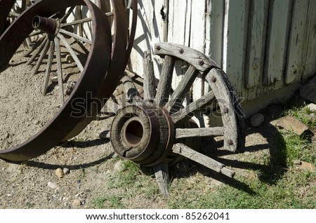 Broken and discarded wagon wheels are lined against a barn