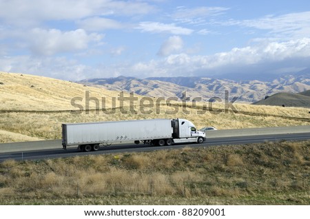 A large semi trailer rig hauls a load from California eastward into the Sierra Nevada Mountains