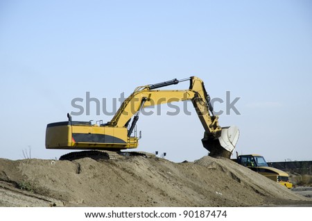 Power shovel and dump truck work together to excavate soil on bridge construction project