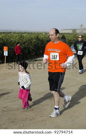 BAKERSFIELD, CA - JAN 14: Father and daughter run the dirt path cross country leg of the Rio Bravo Rumble biathlon (running and mountain biking) on January 14, 2012, in Bakersfield, California.