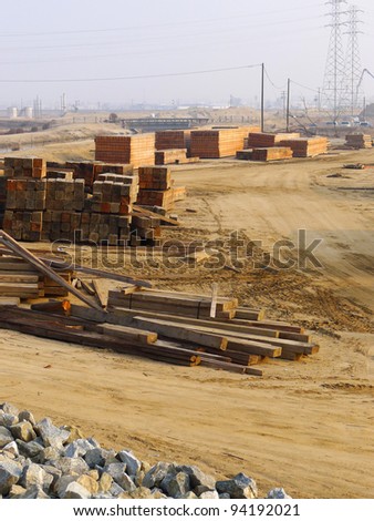 Contractor\'s lay down area for storage of wooden timbers, sheets and planks used on a bridge construction project