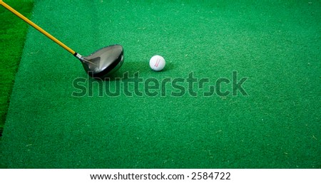 Photo of a golf driver being held to the tee getting ready to hit the ball.