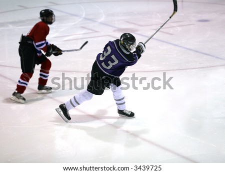 Player going through a follow-through taking a slapshot in offensive end.  Good form and body positioning.