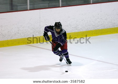 Hockey player looking down at the puck as he skates forward.