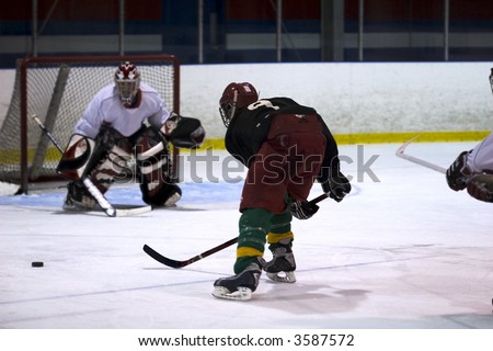 Player races to the puck with opposing goalie waiting for shot