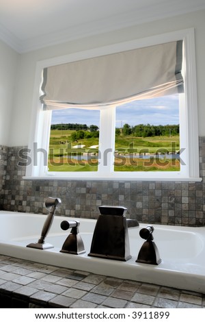 Bathroom interior of a model home with a golf course visible outside the window
