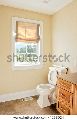 Interior of a home.  Washroom with oak furnishing and a roman shade on the window.