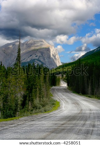 Conceptual rocky road to the top of the mountain.  Cloud covered peaks at the end of the road in Alberta, Canada.