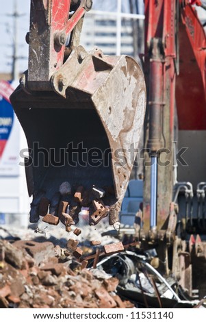 Heavy red construction machinery dropping broken bricks into a pile