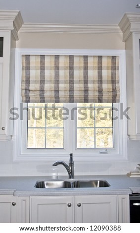 Kitchen sink with window looking outside.  Roman shade is the window covering.