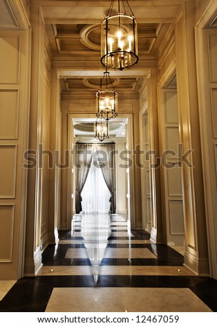 Narrow hallway leading to a room with a grand window with elegant drapes
