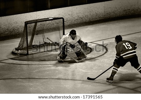 Goalie maintains strong focus while he concentrates on opponent bearing in on breakaway.  Photoshop used to create a grungy look to the photograph.