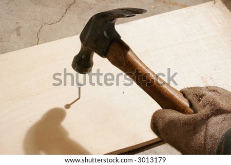 A hammer swinging at a nail.