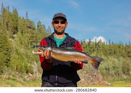 Fisherman caught a nice male salmon in the north river. Varzuga river, Kola Peninsula, Russia.