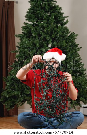 A man attempts to untangle a string of Christmas lights in front of an undecorated Christmas Tree.
