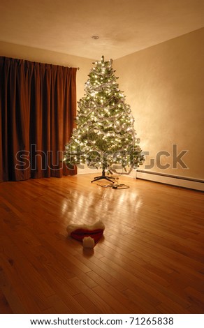 A Santa hat sits on the floor in front of a Christmas Tree.