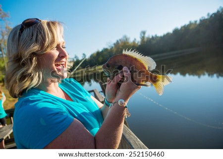 adult woman holding fish she caught on vacation