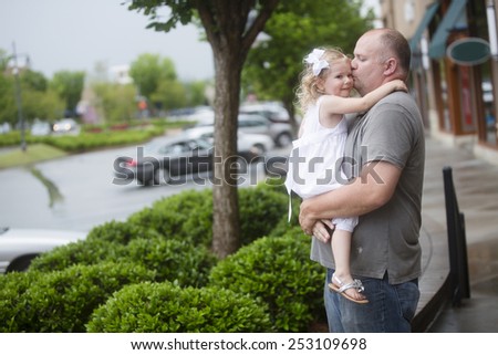 father kissing daughter outdoors at mall