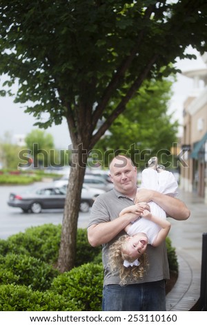 dad playing with daughter, holding little girl upside down