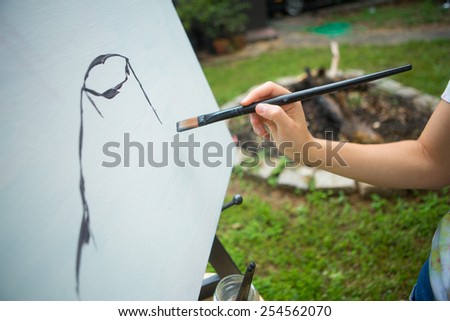 young woman painting on canvas outside