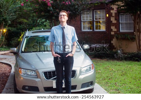 young man standing in front of car outside in front of new home
