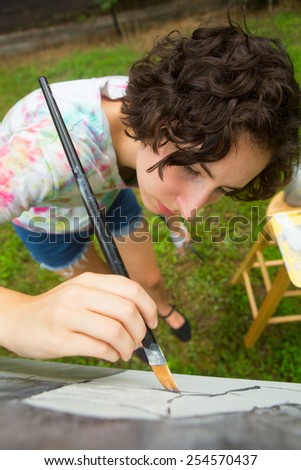 young caucasian woman painting on canvas outside
