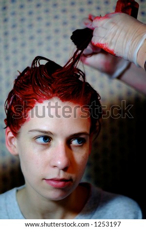 A young woman in the process of having her hair dyed red.