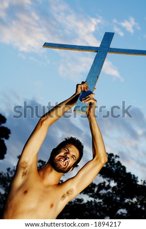 A man raising the cross above his head and smoking a ciggarette.