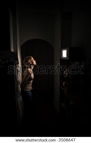 Young woman alone in her apartment, waiting for the microwave to finish her meal.