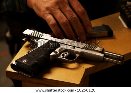 Semi Automatic pistol sitting on a table, slide locked back and clip removed, it is unloaded.