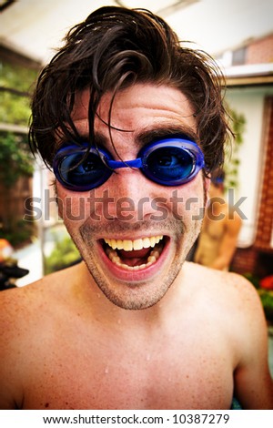A young man with swimming goggles having tons of fun at the pool.