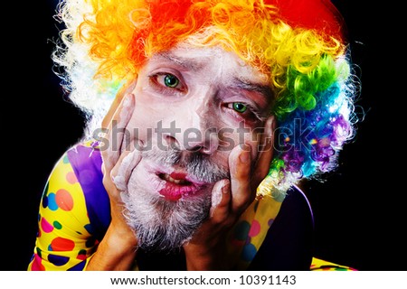 Terrifying clown applying makeup and looking sad and vulnerable. He is about to snap.