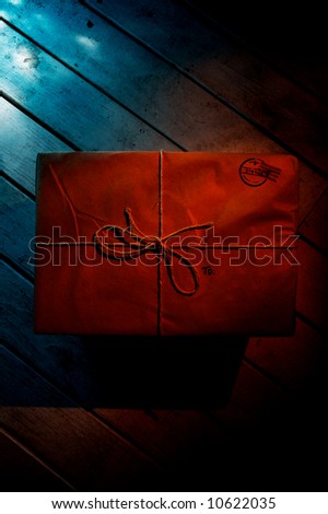 A mysterious package sitting on a wooden floor. It is illuminated only by a small house light.