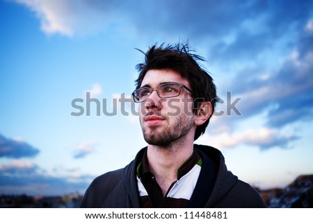 Young man on the rooftops, gazing into the sunset. A beautiful sky around him.