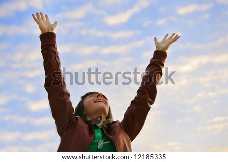 A happy young woman reaching her arms to the sky.