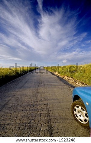 Road to nowhere. A car about to runaway on an old road, over the blue sky