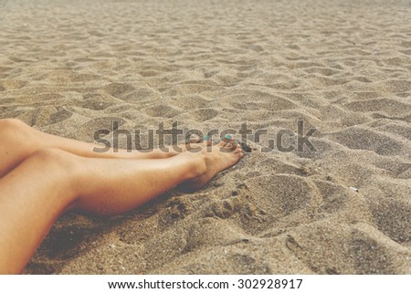 Relax at the beach - close-up of woman\'s legs over the sand