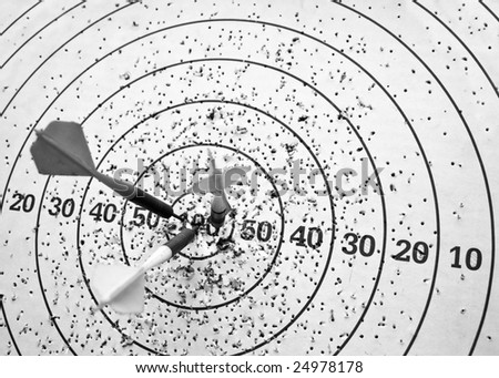 Close up image of three arrows hit the center of dartboard; In black and white