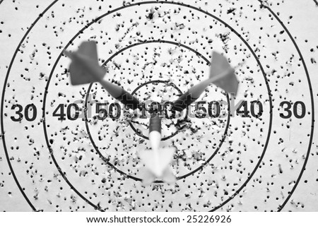Close up image of three arrows hit the center of dartboard; In black and white