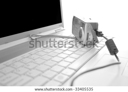 photo camera with data cable on a laptop