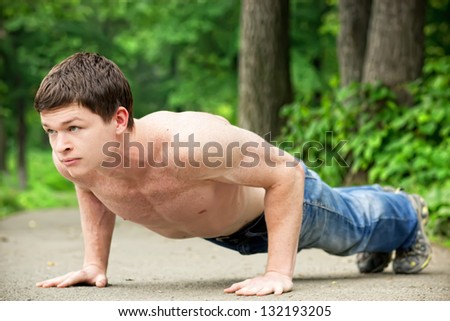 Push ups workout. Young caucasian man making pushups outdoors.