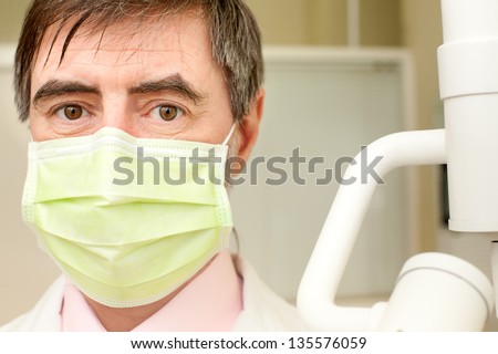 Closeup portrait of happy middle-aged dentist in his cabinet