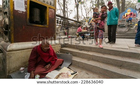 KATHMANDU, NEPAL - CIRCA MARCH 2014: Monk sits at the main entrance of Swayambhunath or Monkey temple. The temple is protected as the UNESCO world heritage site.