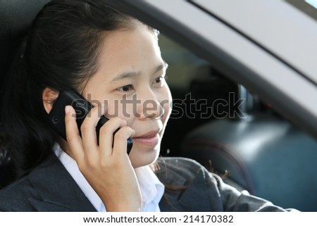 businesswoman driving car and talking on cell phone concentrating on the road