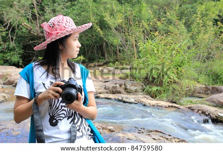 woman holding a camera, forest and water fall background
