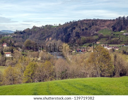 Asturian fields situated in the mountains of Asturias spain, you can see some rural houses and a river with a bridge